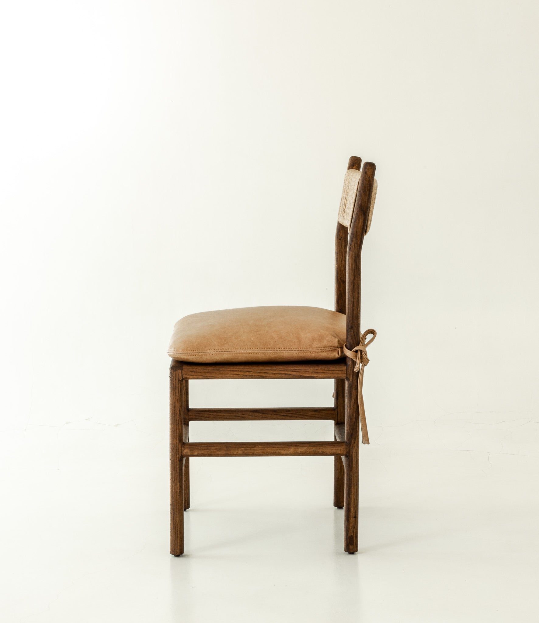Romi solid oak dining chair in chocolate colour way with leather pillow - side angle 