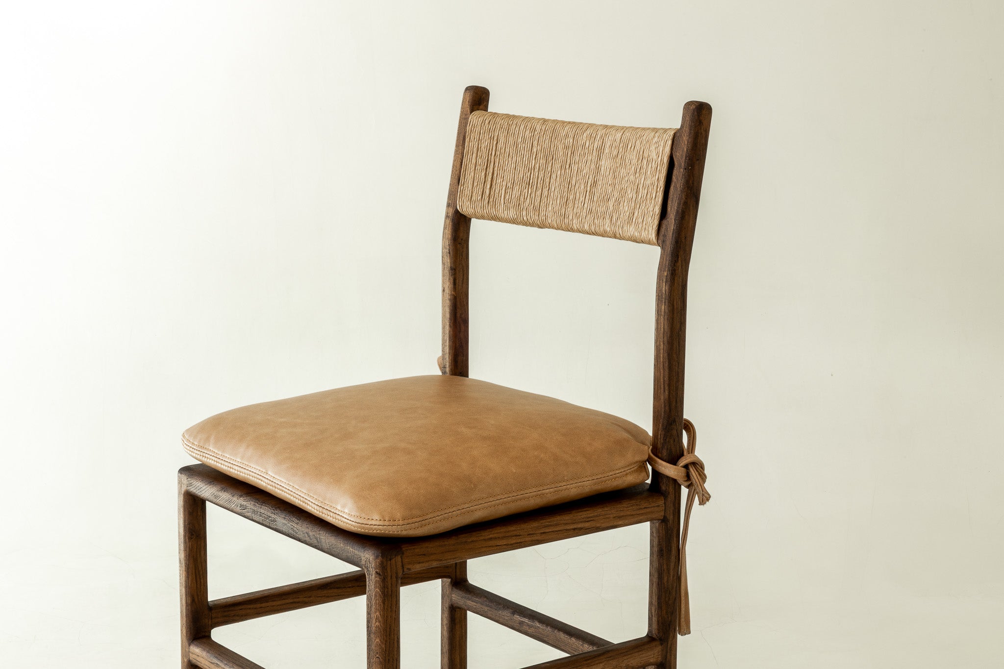 Romi solid oak dining chair in chocolate colour way with leather pillow - close up front angle 